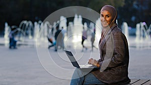 Busy successful muslim student girl in hijab young islamic business woman using laptop app working in city fountains