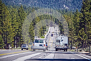 Busy traffic, including RVs on road surrounding South Lake Tahoe with forest and mountains