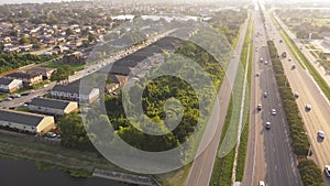 Busy traffic on Interstate 10 highway near Lake Barrington early morning along row of townhouses, condos, lush green trees and