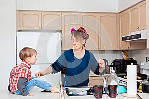 Busy white Caucasian young woman mother housewife with hair-curlers in her hair cooking preparing dinner meal in kitchen