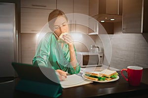 Busy woman eating, drinking coffee, talking on the phone, working on a laptop at the same time. Businesswoman doing