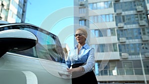 Busy woman getting out of car closing door, hurrying to business meeting