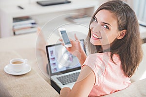 Busy woman at home using mobile phone and laptop at the same tim