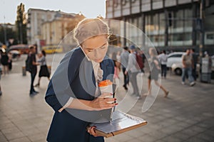 Busy woman is in a hurry, she does not have time, she is going to eat snack on the go. Worker eating, drinking coffee