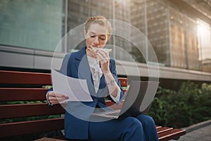 Busy woman is in a hurry, she does not have time, she is going to eat snack outdoors. Worker eating and working with