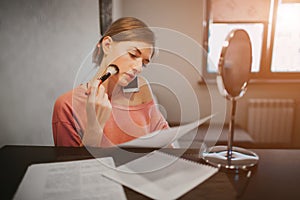 Busy woman making a make-up, talking on the phone, reading documents t the same time. Businesswoman doing multiple tasks