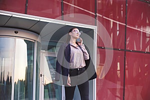 Busy woman is phoning when leaving an office building