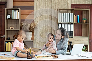 Busy woman trying to work while babysitting two kids.  Young Asian mother talking and playing with two children playing around her