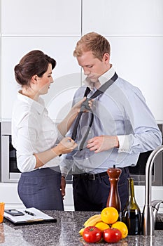 Busy woman tying husband's tie