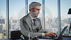 Busy worker typing laptop at cityscape view. Handsome executive checking project