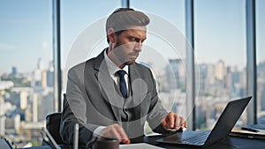 Busy worker typing laptop at cityscape view. Handsome executive checking project