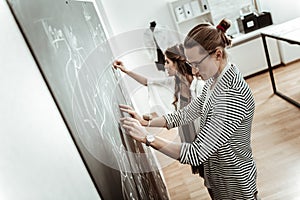 Handsome long-haired dressmaker in eyeglasses and a pretty model looking busy