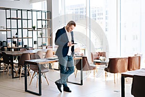 Busy young business man wearing fashion suit clothing is using mobile phone in modern office