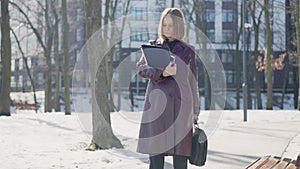 Busy young businesswoman sighing walking away on cold winter day in city. Portrait of Caucasian serious concentrated