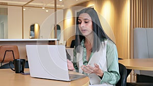 Busy young Indian woman having virtual meeting hybrid working in office.