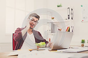 Busy young man has business lunch in modern office interior