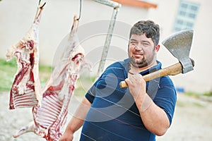 Butcher with axe and sheep carcass meat