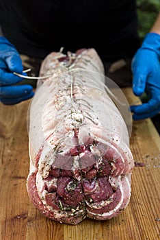 Butcher binds meat rolled up for pochette roast pork