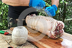 Butcher binds meat rolled up for pochette roast pork