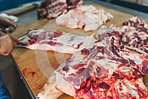 butcher cut raw meat of a pig with a knife at the slaughterhouse, cutting pork