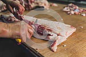 butcher cut raw meat of a pig with a knife at table in the slaughterhouse