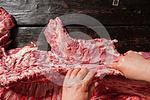 Butcher cuts raw pork chop. wooden background