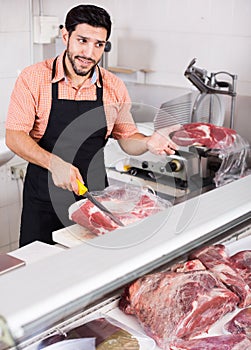 Butcher is cutting meat for clients