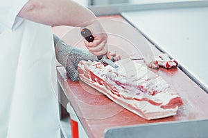 Butcher cutting meat for further processing with knife