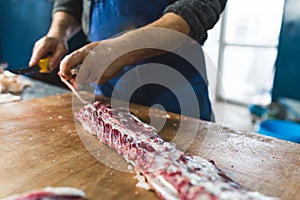 a butcher cutting pig ribs on the wooden table, closeup shot slaughterhouse
