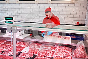 Butcher cutting raw lamb ribs in a butcher shop