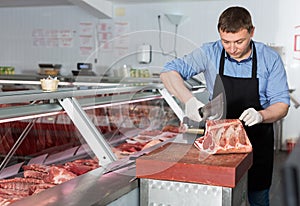 Butcher cutting raw steak on ribs