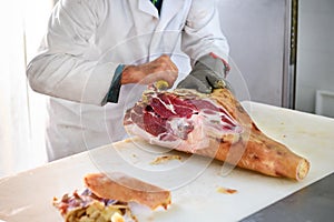 Butcher deboning a leg of prosciutto ham