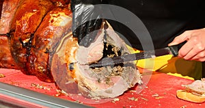butcher with glove cuts slices of porchetta a pork salume