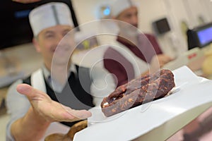 Butcher presenting chorizo sausage to customer