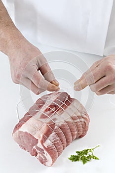 Butcher prparingng raw rolled meat enclosed