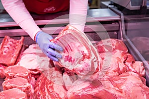 Butcher`s hands holding meat piece. Offering fresh meat at display in supermarket