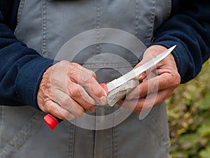 The butcher`s hands sharpen a knife on a stone. photo