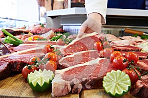Butcher Showing Customer Sirloin Steak In Refrigerated Display