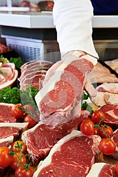 Butcher Showing Customer Sirloin Steak In Refrigerated Display