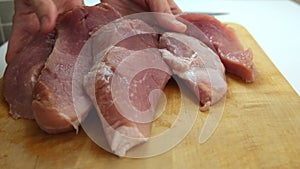 A butcher showing cut sliced pork meat close up, selling fresh organic meat at a market