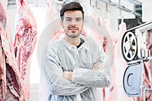 Butcher in slaughterhouse in front of swine halves