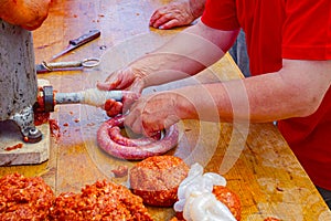 Butcher is stuffing pig intestine with minced meat to make sausages