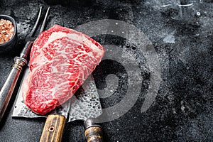 Butcher table with wagyu Rib Eye steak, raw beef meat. Black background. Top view. Copy space