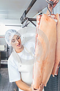 Butcher woman cutting meat for further use