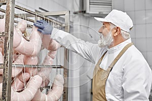 Butcher working with modern production of sausages.