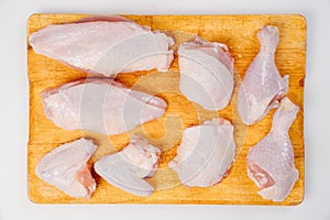 Butchered carcass of raw chicken on a wooden cutting board on a white background