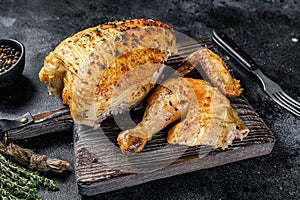 Butchered grilled whole chicken. Black background. Top view