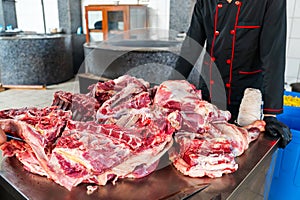 Butchering was done by a butcher cook in a restaurant. man in uniform touching fresh meat on stall while working in