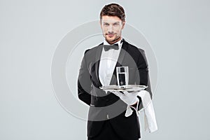 Butler in gloves holding glass of water on silver tray