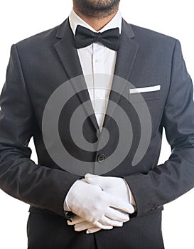 Butler, waiter with tuxedo and bow tie, folded gloved hands ready to serve, standing on white background